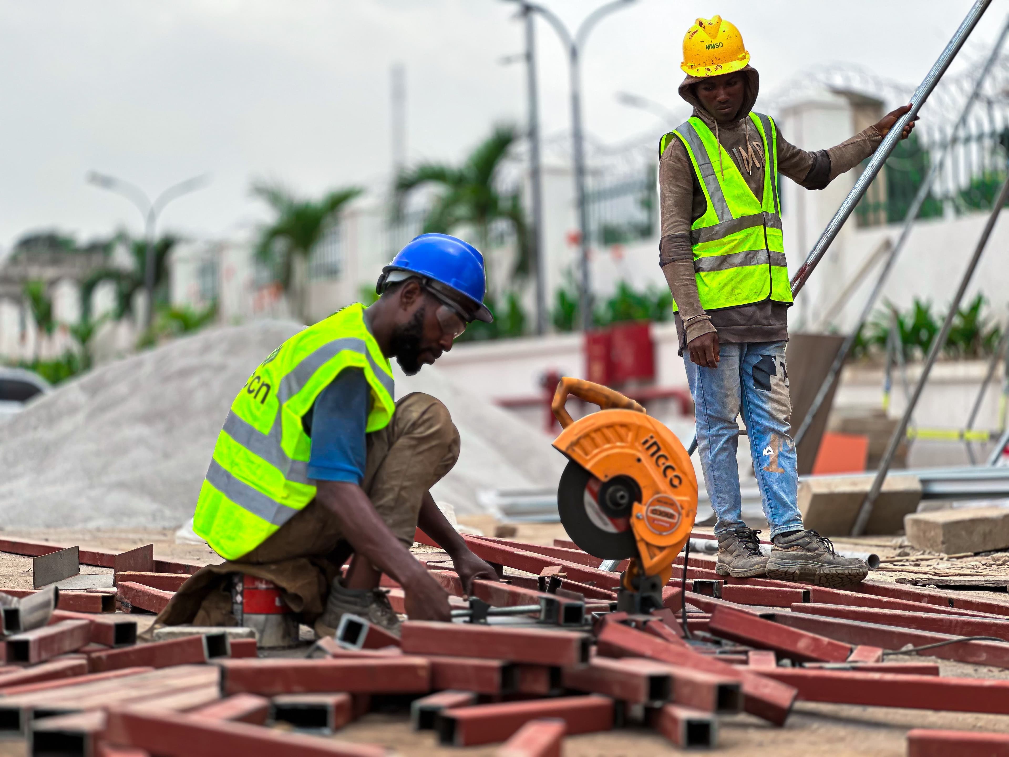 Two contractors working with a cut-off saw on steel beams at a job site