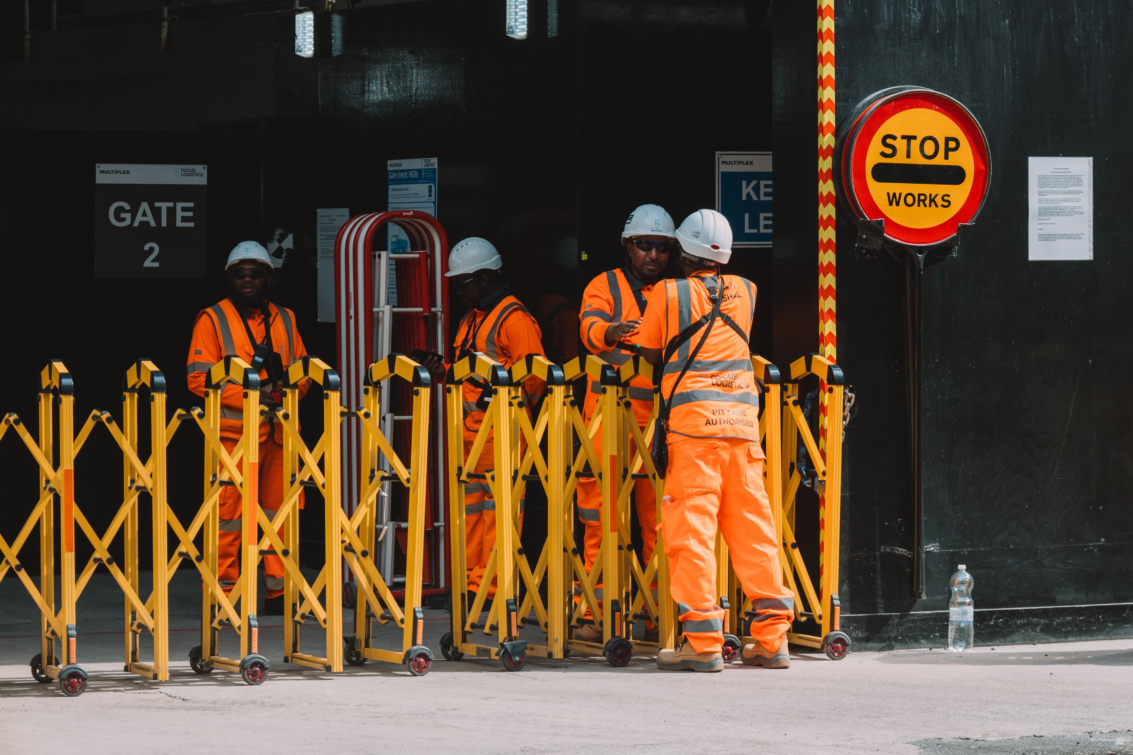 A crew of contractors in hi-vis gear gathered at a site entrance