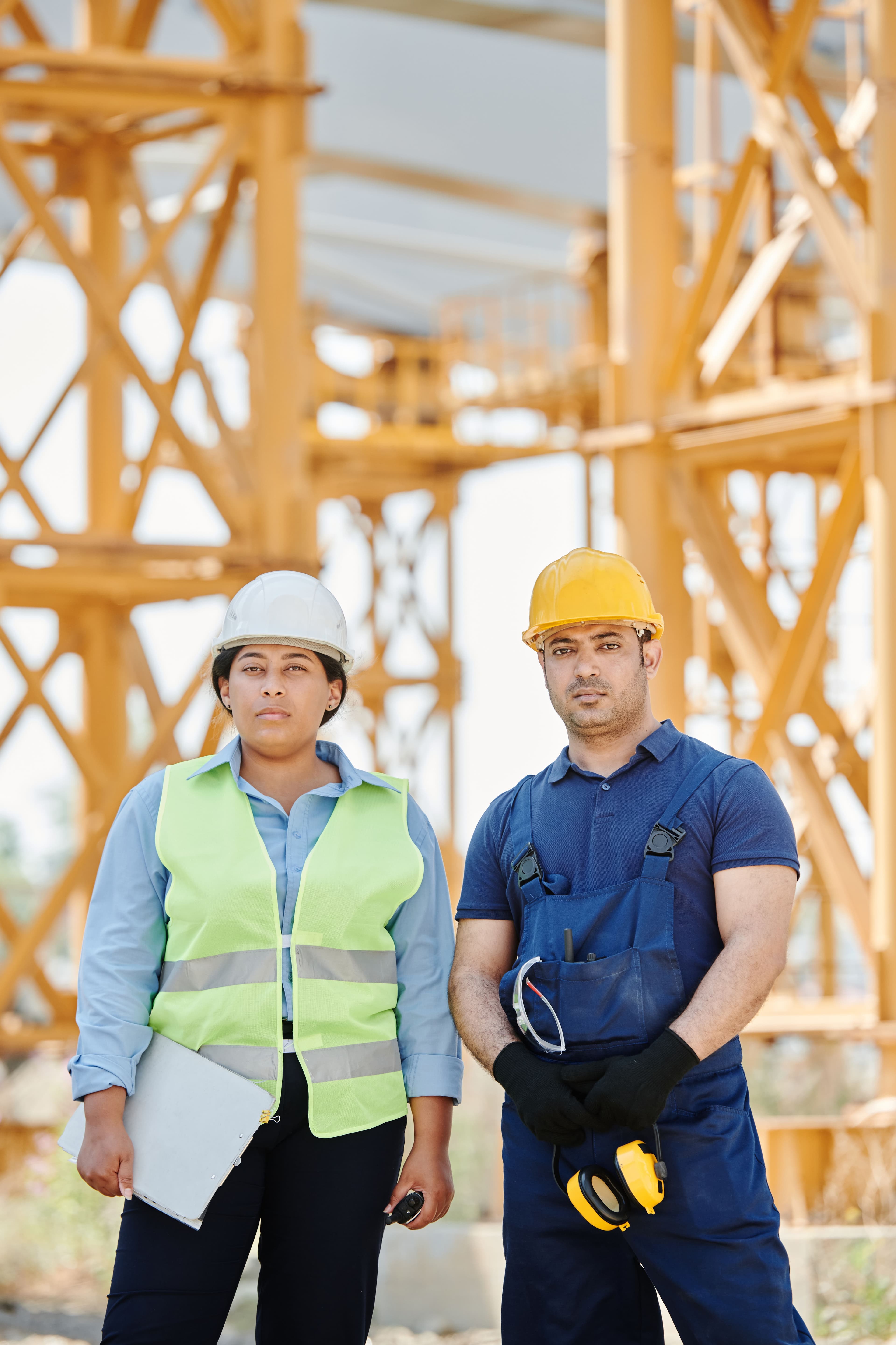 Two contractors in hard hats standing together at a steel-framed job site