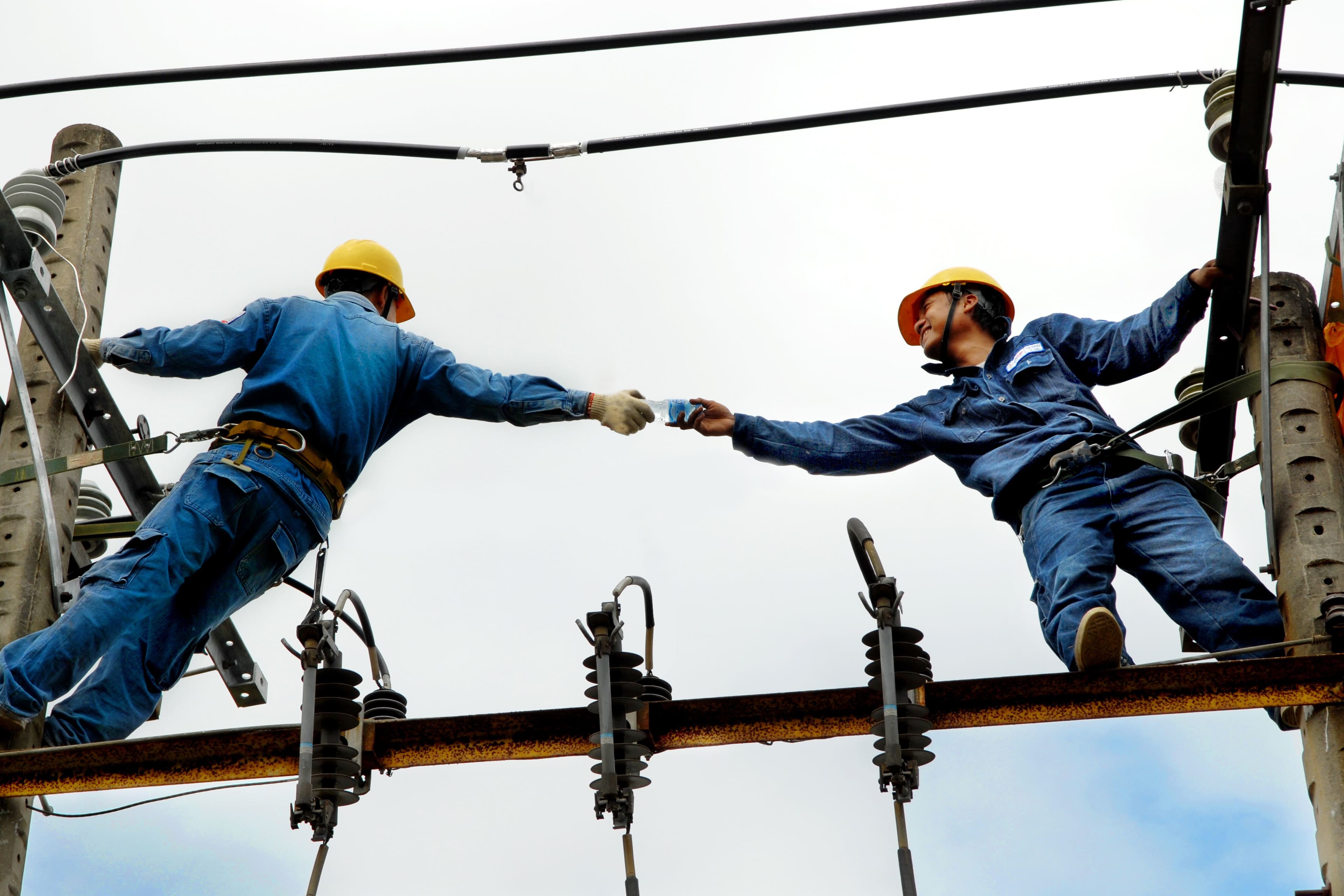 Two linemen working together on a utility pole